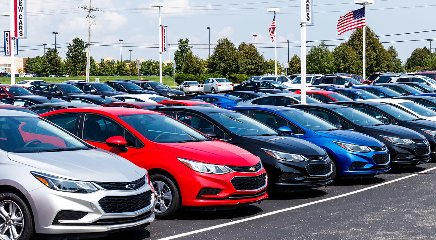 Several cars parked in a neat row in a parking lot, displaying a mix of colors and styles.